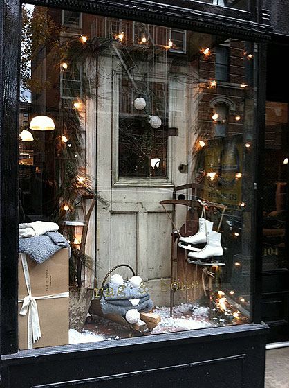 a store front with christmas lights and decorations in the window, on a city street