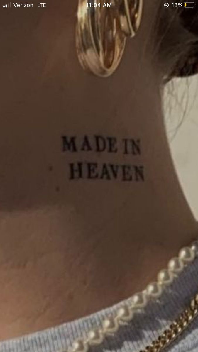 the back of a woman's neck with words written on it and two gold hoop earrings