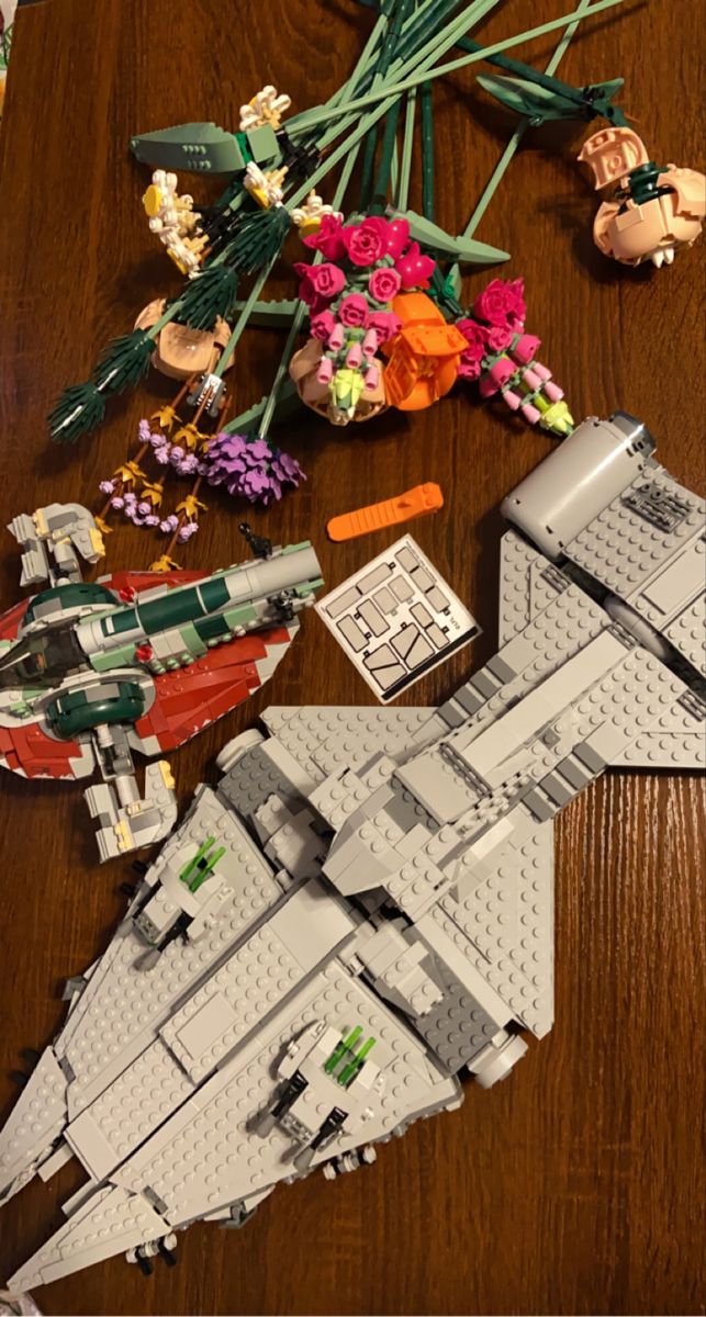 a lego model is laying on a table next to some flowers and other items that are scattered around it