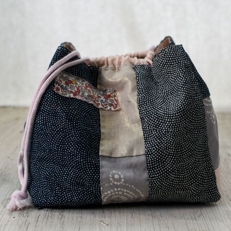 a black and white patchwork bag sitting on top of a wooden floor next to a wall