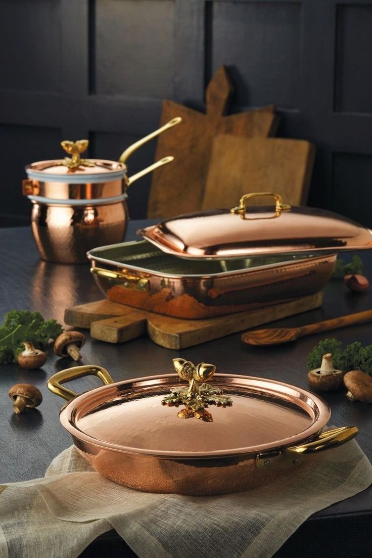 copper pots and pans sitting on top of a table