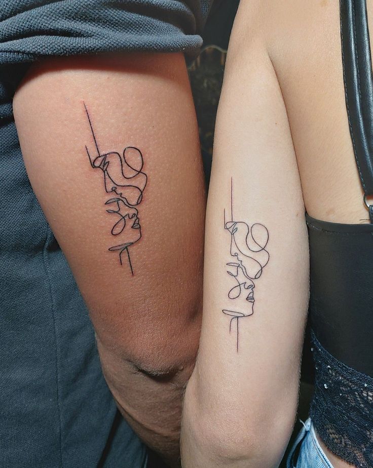 two people with matching tattoos on their arms, one is holding the other's arm