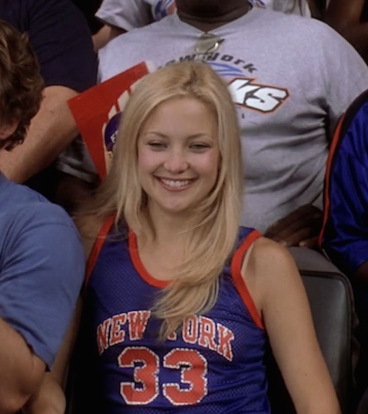 a young woman sitting in the stands at a basketball game wearing a new york jersey