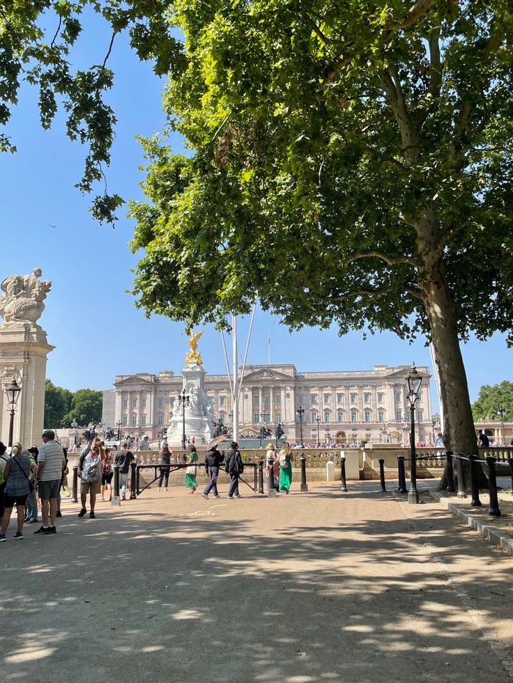 many people are walking around in front of a building with trees on the side walk