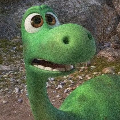 a green dinosaur with big eyes standing in front of rocks