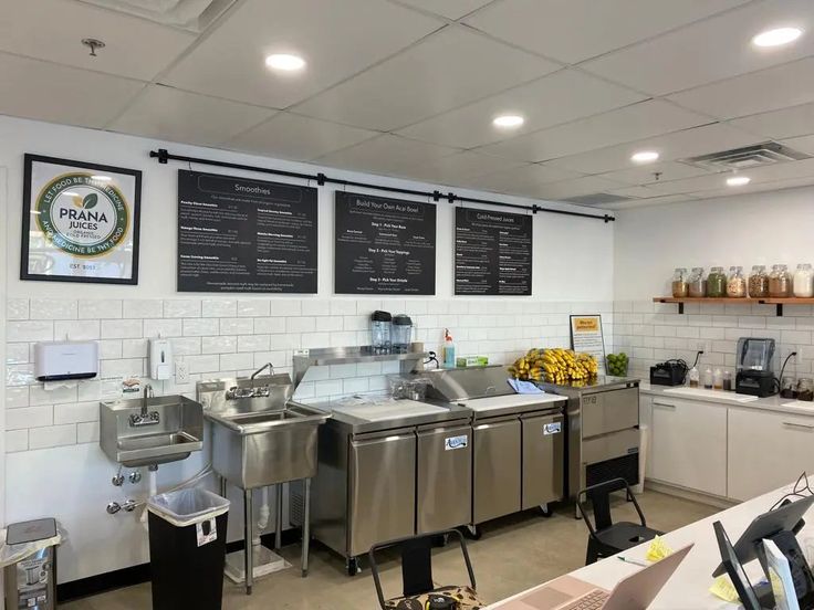 the interior of a restaurant with stainless steel appliances and menus hanging on the wall