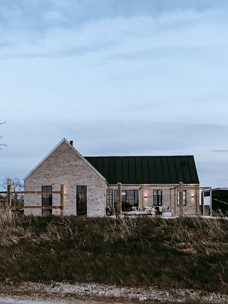 an old brick house sitting on top of a grass covered field next to a tree