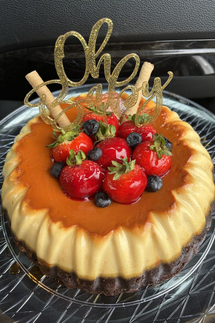 a cake with strawberries and blueberries on top sitting on a glass platter