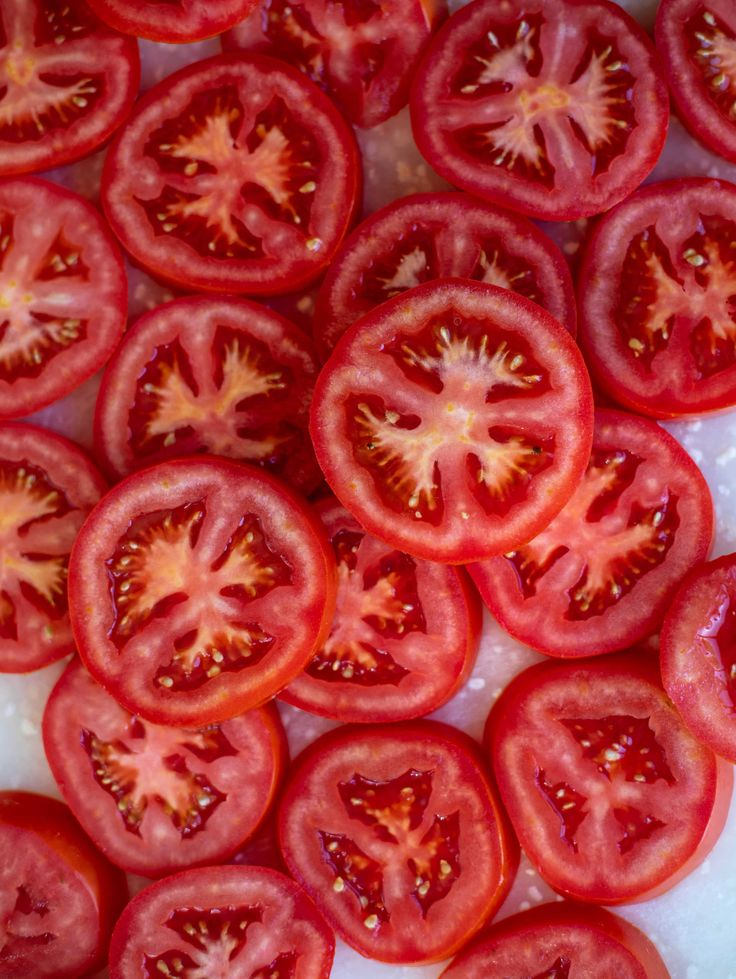 sliced tomatoes on a cutting board ready to be cut