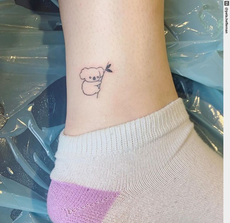 a small tattoo on the ankle of a woman with a sheep behind her head and an arrow