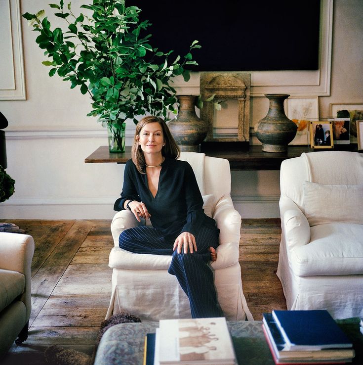 a woman sitting in a white chair next to a potted plant on a table