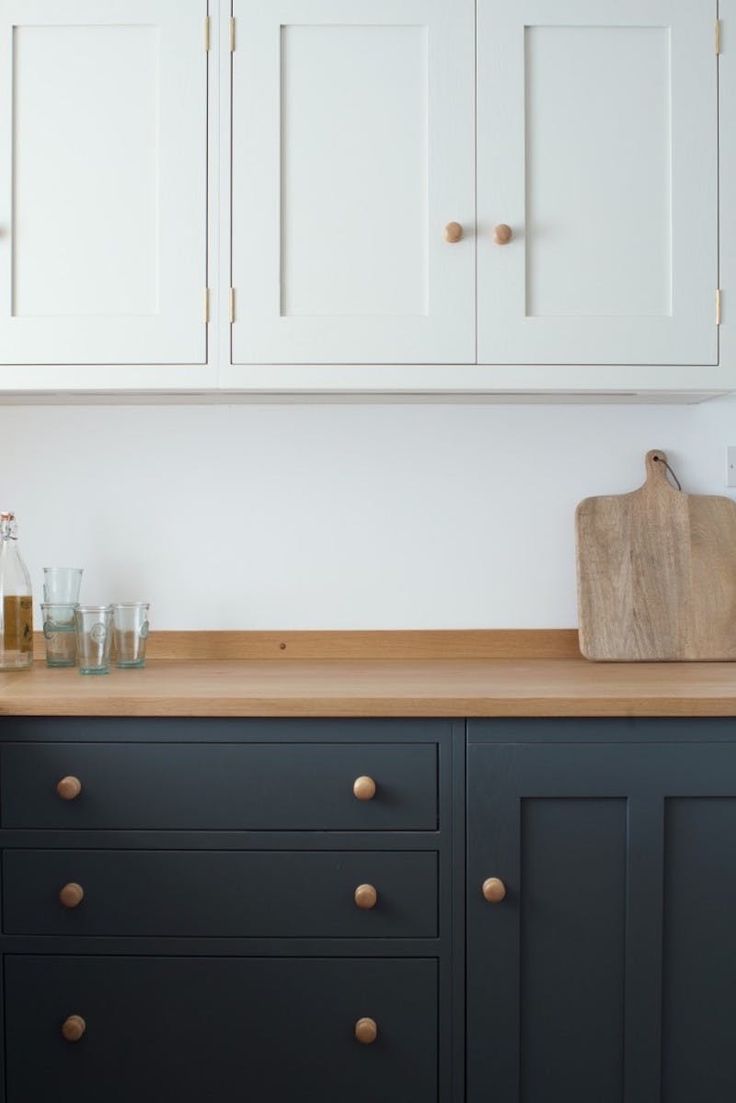 a kitchen with white cabinets and wooden counter tops, including a cutting board on top of the cabinet doors