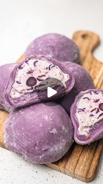 three purple doughnuts on a cutting board with an ice cream topping in the middle