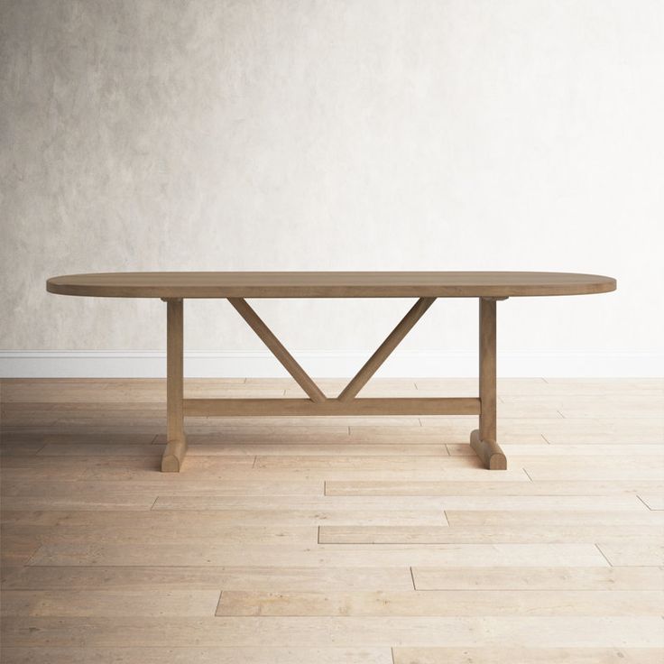 a wooden table sitting on top of a hard wood floor next to a white wall