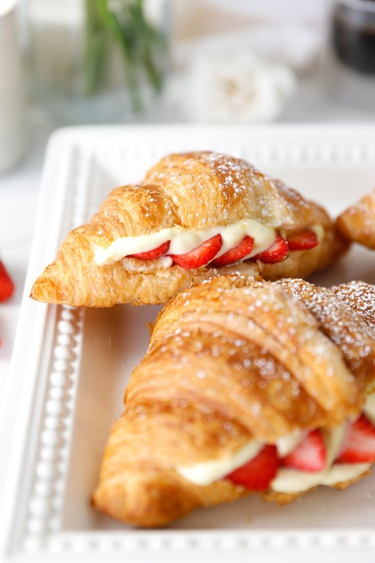 two croissants with strawberries and cream on them