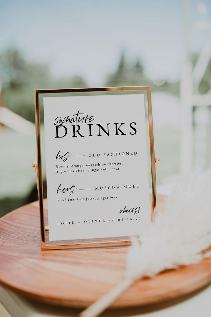 a sign that is on top of a wooden table next to a white and black feather