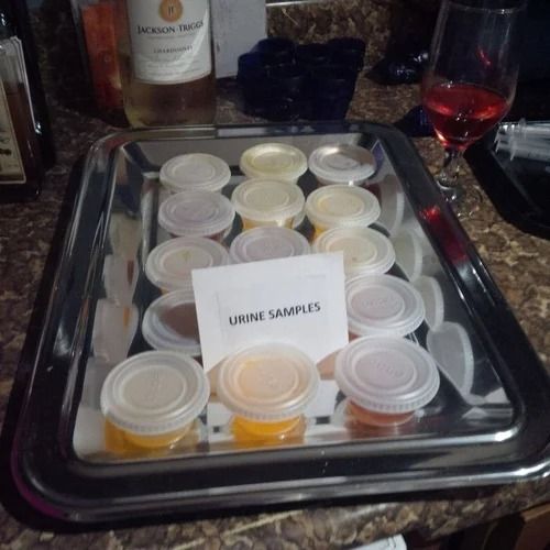 there are many small cups on the tray with some wine in the glass behind them