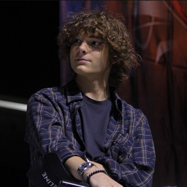 a young man with curly hair sitting down