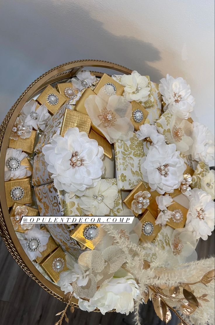 a close up of a basket filled with flowers and gift wrapped in gold foil paper