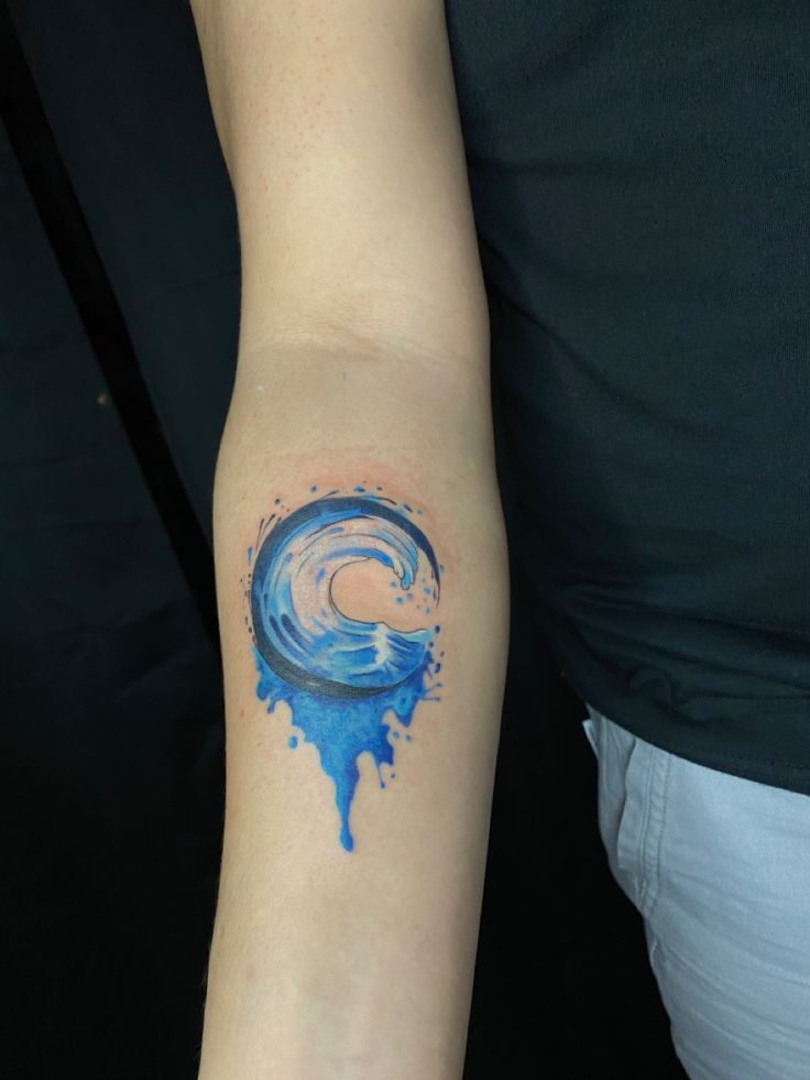 a woman's arm with a blue wave tattoo on it