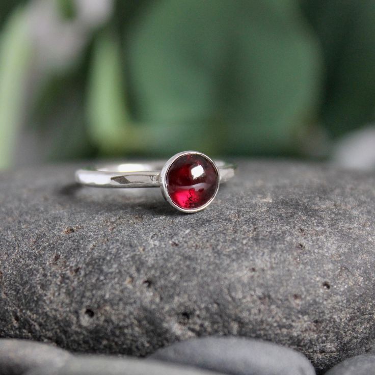 Garnet symbolizes love and is the gemstone to give for the 2nd anniversary. It is also the birthstone for January. This simple sterling silver stacking ring is a great gift, or an addition to a collection of stacking rings. Here are the details: This ring is made with a 4mm or 5-6mm bezel set garnet cabochon set on a sturdy sterling silver band handmade in your size. It can be worn with other stackable rings, or by itself.Please select your ring size. Sizes are US based. Sterling Silver Stackable Rings With Bezel Setting As Gift, Sterling Silver Stackable Rings, May Birthstone Gift, Classic Everyday Sterling Silver Birthstone Ring, Silver Stackable Rings With Round Stones For Gift, Red Gemstone Sterling Silver Stackable Rings, Red Gemstone Stackable Rings In Sterling Silver, Sterling Silver Stackable Rings For Anniversary - May Birthstone, Classic Everyday Stackable Gemstone Rings, Red Stackable Rings With Bezel Setting As Gift