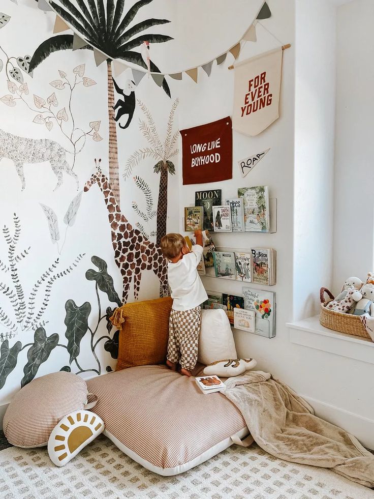 a child is playing on the bed in his bedroom with giraffes painted on the wall