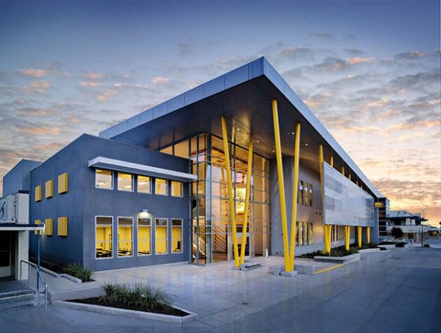 an office building is lit up at night with bright lights on the windows and yellow poles