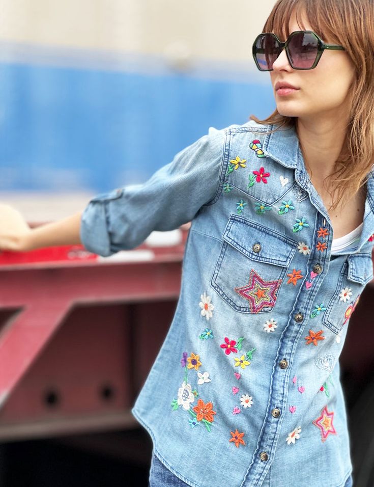 a woman in sunglasses is leaning against a red truck with her hand on the back of it