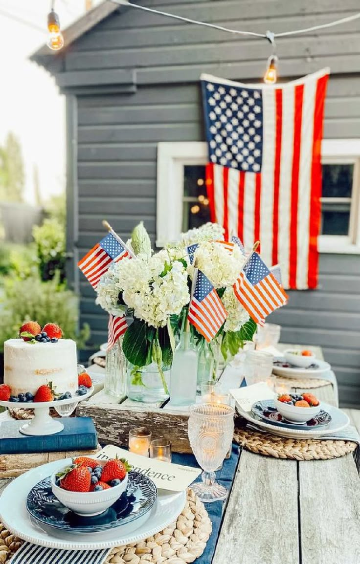 a table topped with cake and flowers on top of a wooden table next to an american flag