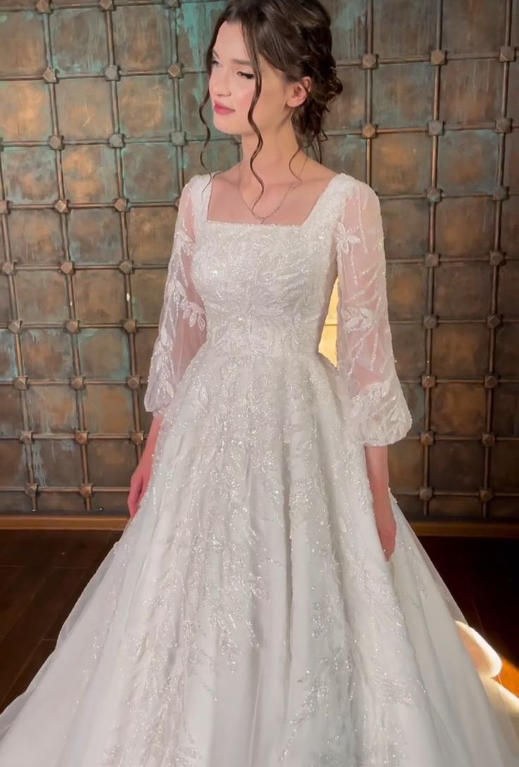 a woman in a white wedding dress standing next to a wall