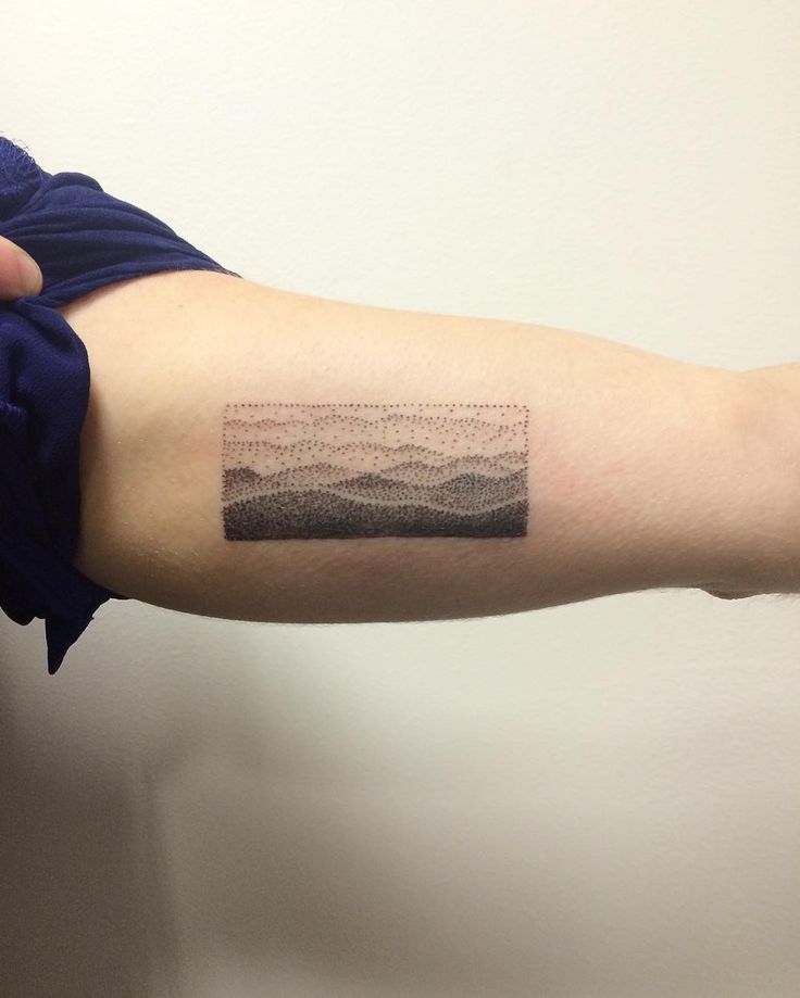 a man's arm with a landscape tattoo on the left side of his arm