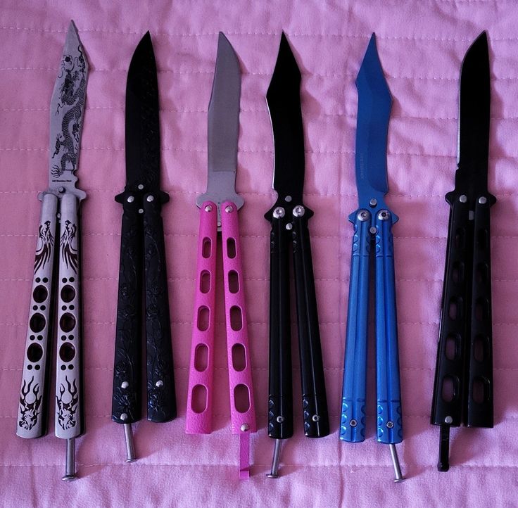 five different types of knifes lined up on a pink sheet with black and blue handles