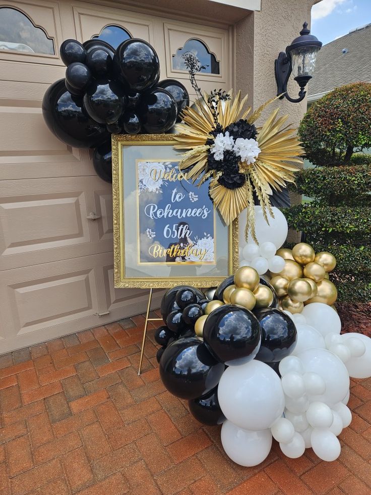 black and gold balloons are on display in front of a house