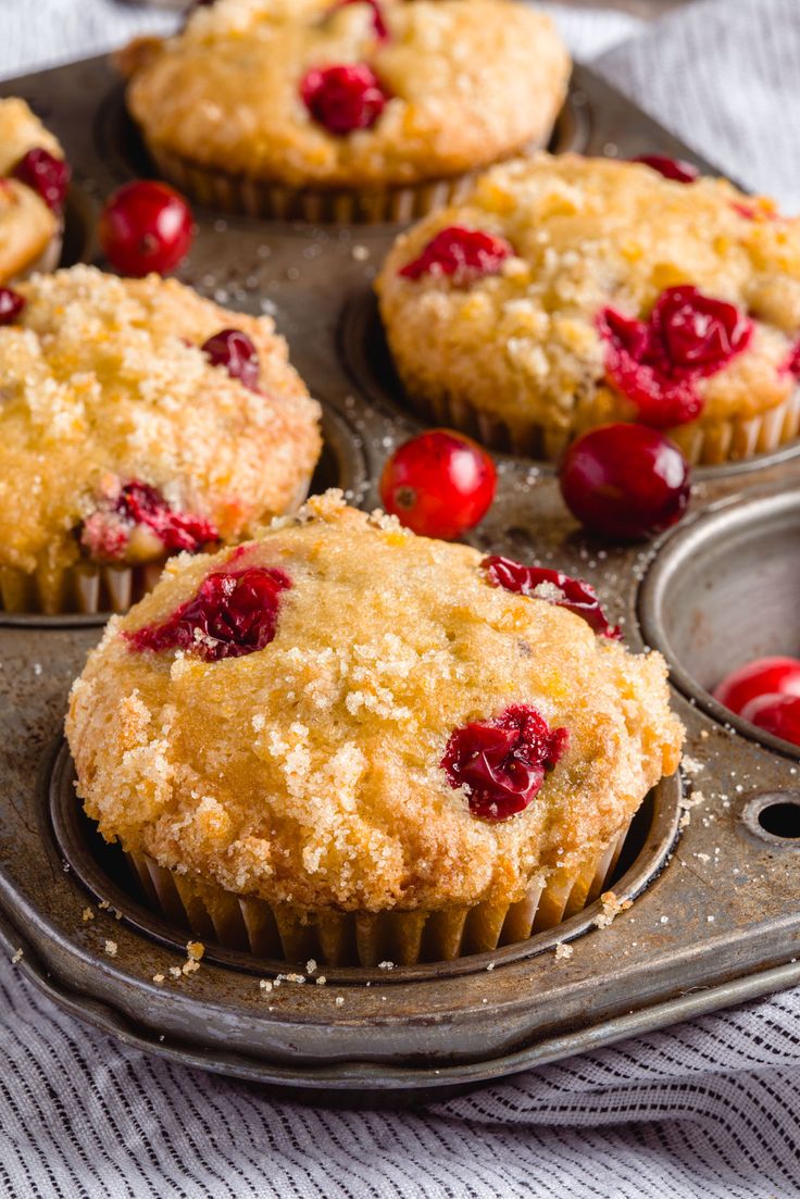 freshly baked cranberry muffins in a muffin tin with cherries