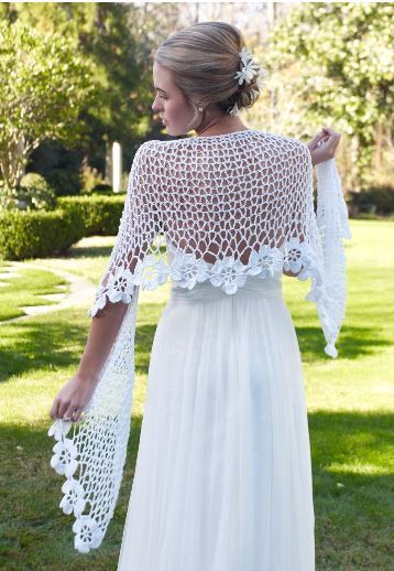 a woman in a white dress is walking through the grass with her arms around her back