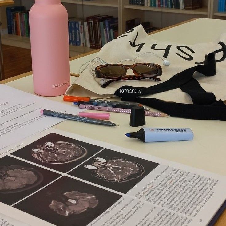 a pink water bottle, sunglasses, and other items on a table in front of books