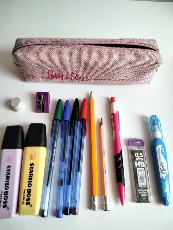 several pens, pencils and markers are lined up next to a zippered pouch