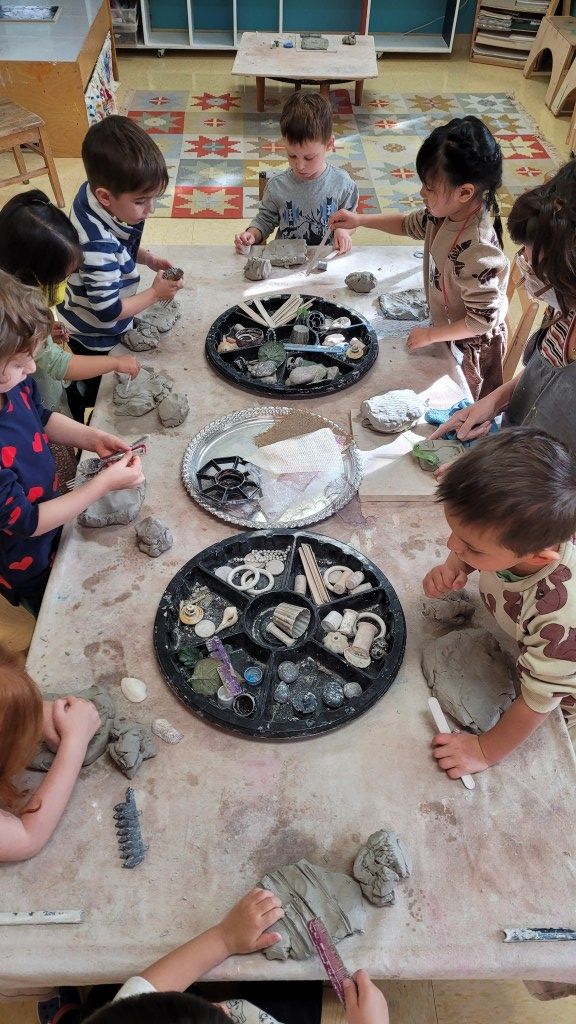 several children are playing with clay at a table