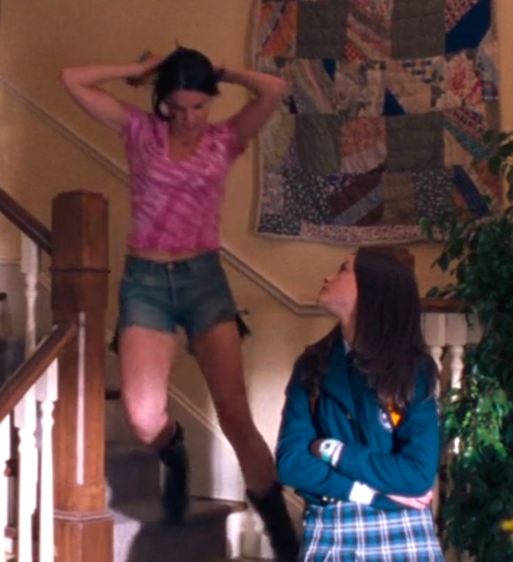 two girls are standing on the stairs and one is holding her head in her hands