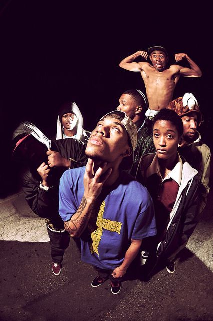 a group of young men standing next to each other in front of a black background