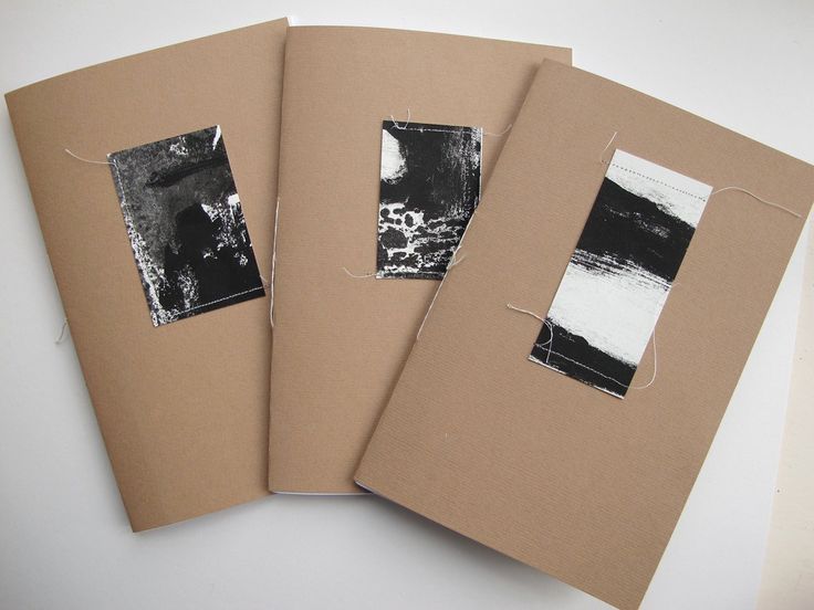 three brown notebooks with black and white pictures on them