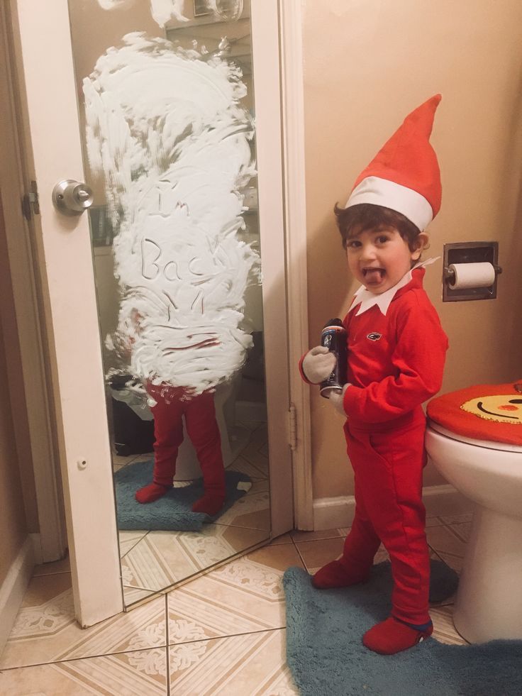 a little boy dressed up as elf standing in front of a toilet with his mouth open