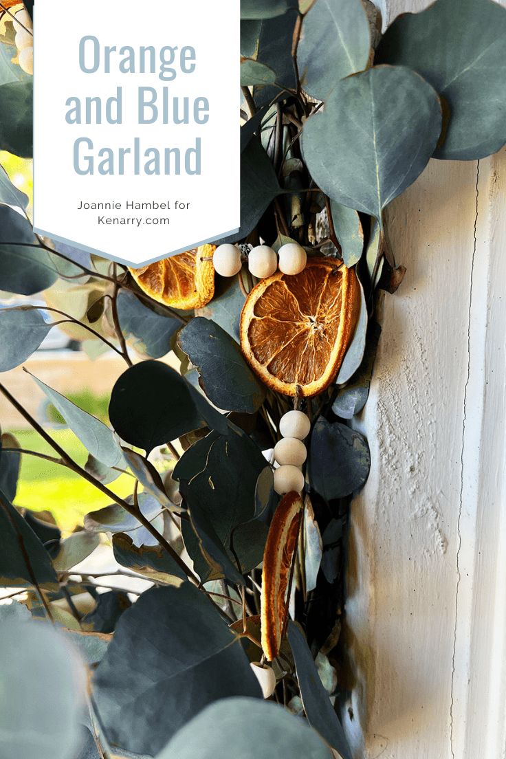 an orange and blue garland hanging on the side of a door with leaves around it