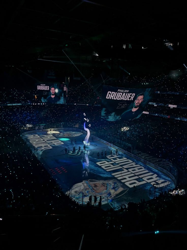 an ice hockey game is being played in the dark with people standing on the sidelines