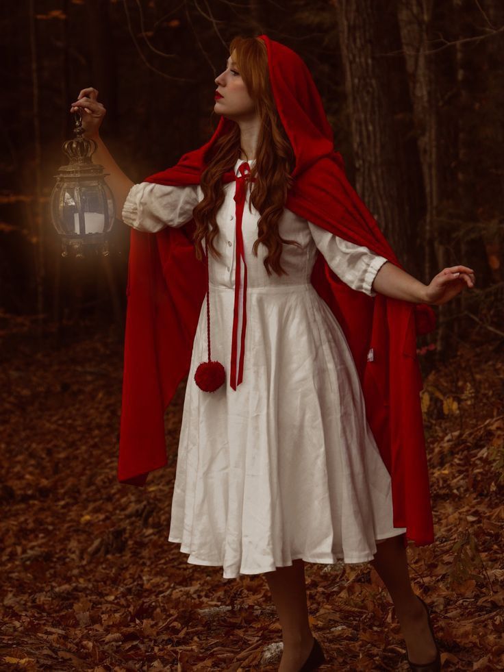 a woman dressed in white and red holding a lantern