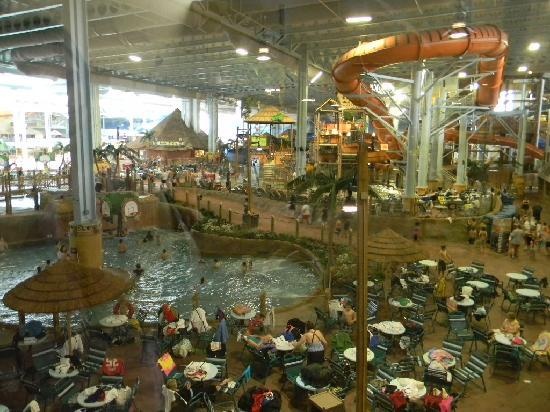 an indoor mall filled with lots of tables and people sitting in chairs next to the water