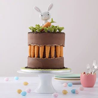 a chocolate cake with carrots and an easter bunny on top