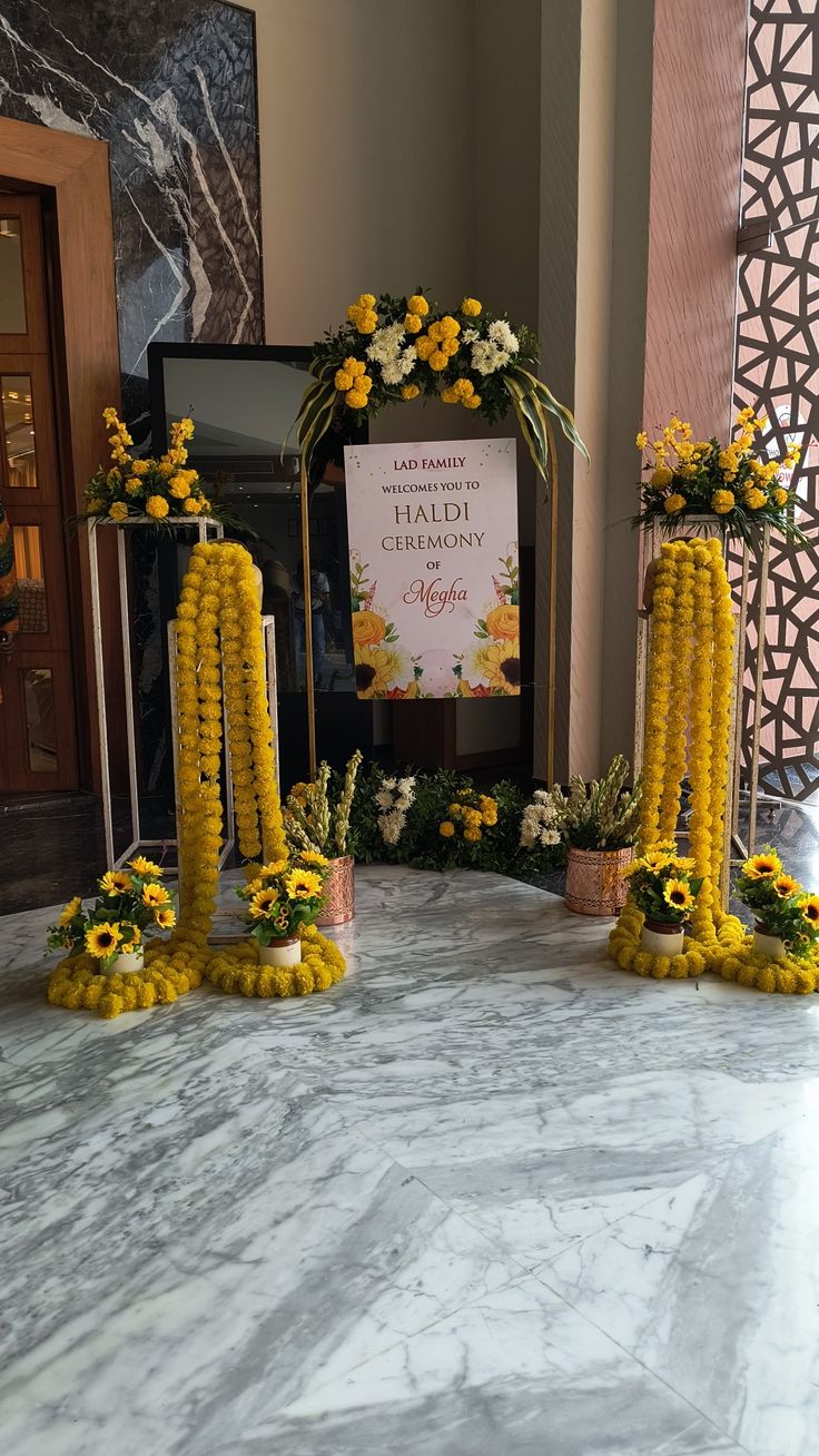 yellow flowers are arranged on the marble floor in front of a sign that reads,