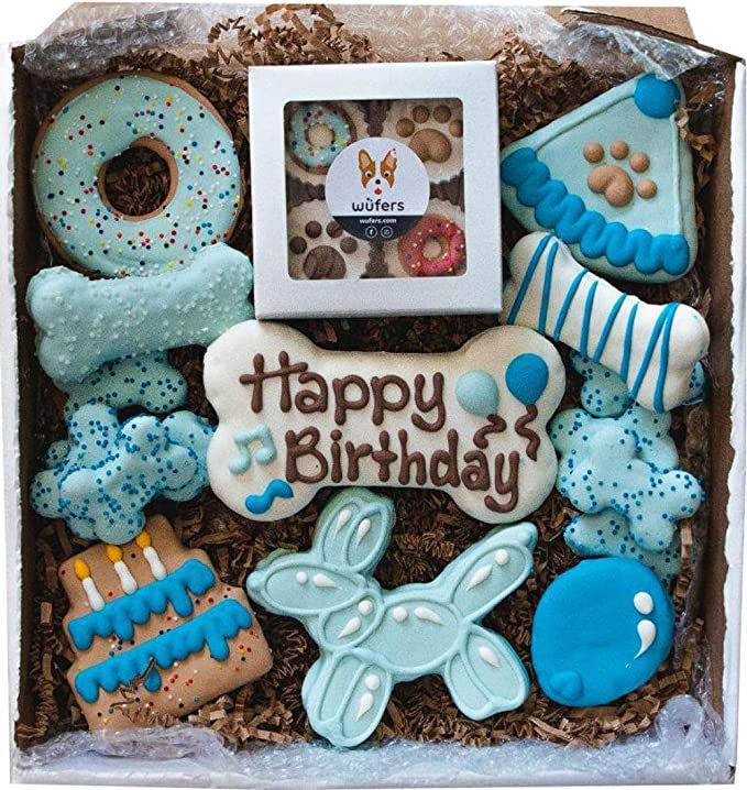 a box filled with lots of decorated cookies and pastries next to a dog's bone