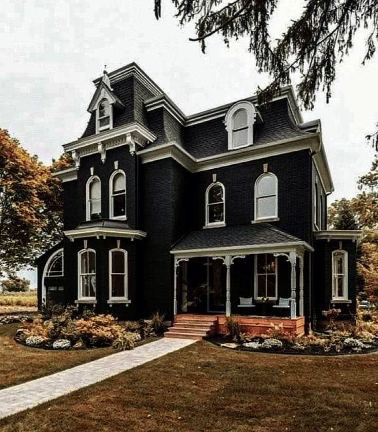 a large black house sitting on top of a lush green field